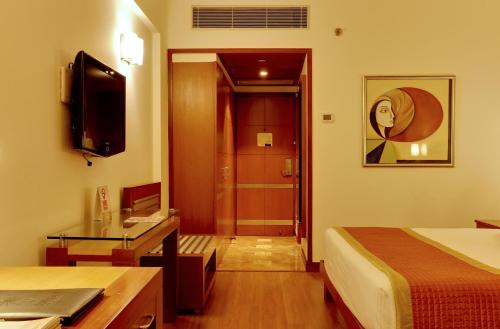 a hotel room with a bed and a television at The Suryaa New Delhi in New Delhi