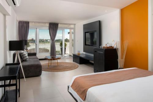 a bedroom with a bed and a couch and a television at TAO Riverside Residence in Phnom Penh