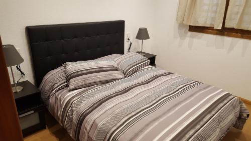 - un grand lit avec une tête de lit noire dans une chambre dans l'établissement Apartamenticos Boggiero II, à Saragosse