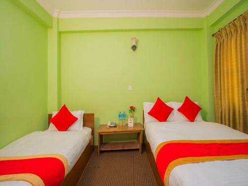 two beds in a room with green walls and red pillows at Waling Fulbari Guest House in Bālāju