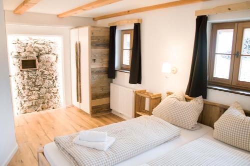 a living room with a bed and a stone wall at Gesindehaus in Diemlern