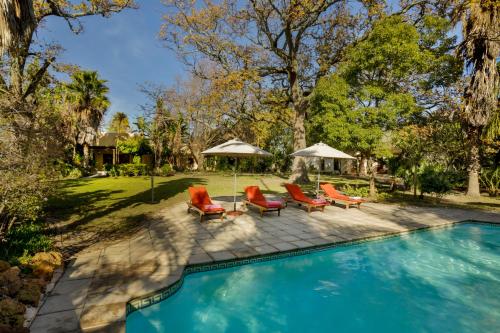 a swimming pool with orange chairs and umbrellas at The Country Guesthouse in Stellenbosch