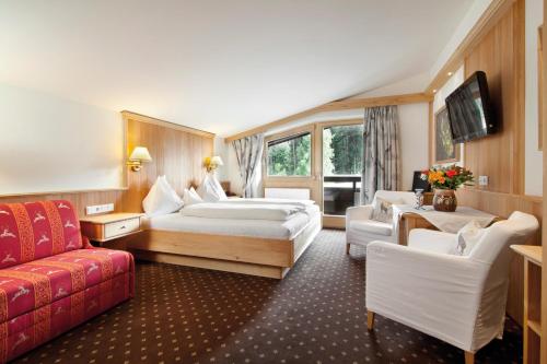 a hotel room with two beds and a couch at Landhotel Föhrenhof Ellmau in Ellmau