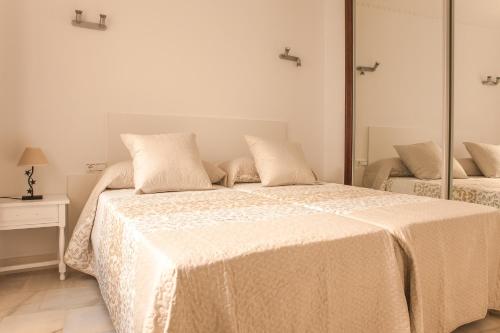 フエンヒロラにあるAurinko 1 Tranquilo y Agradable Apartamento en Los Bolichesの白いベッドルーム(鏡付きベッド1台付)