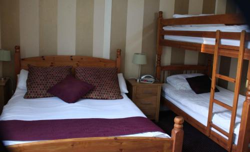 a bedroom with two bunk beds and a night stand at The Dog & Partridge Country Inn in Ashbourne