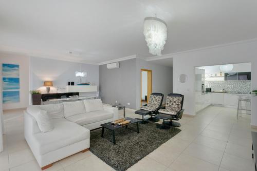 a living room with a white couch and two chairs at Luxury Apt with side Seaviews and Pool, Best Location by Buena Vista in Sliema