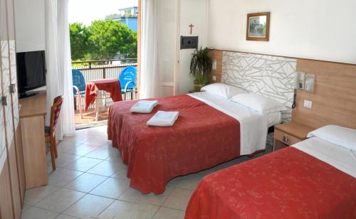 a hotel room with two beds and a balcony at Hotel Zenith in Cervia