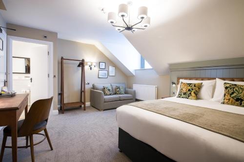 a hotel room with a large bed and a desk and a chair at The Foxglove by Innkeeper's Collection in Kirkburton