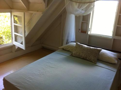 Bett in einem Zimmer mit 2 Fenstern in der Unterkunft Spice Cottage in Five Islands Village