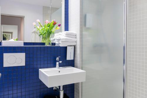 a bathroom with a white sink and blue tiles at Tulip Inn Antwerpen in Antwerp