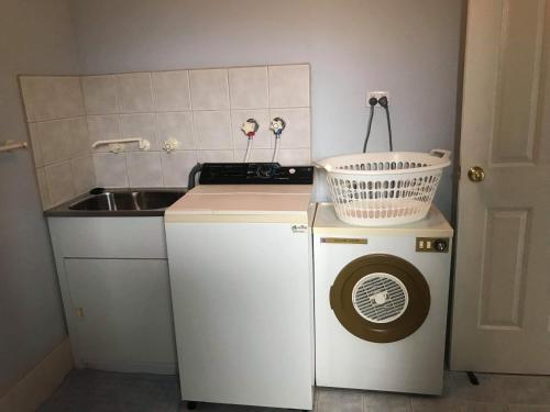 uma pequena cozinha com um lavatório e uma máquina de lavar roupa em Guesthouse on Dolphin em Safety Bay