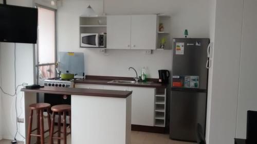 a kitchen with a refrigerator and a counter with stools at Dpto La Serena in La Serena