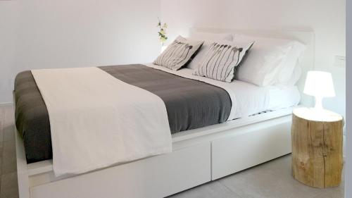 a white bedroom with a large white bed with a wooden stump at C come Colorato in Como