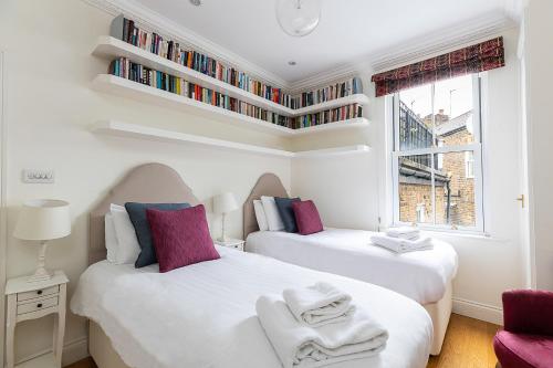 two beds in a room with bookshelves on the wall at ALTIDO Stunning 3 bed, 2 bath house with garden and rooftop terrace in London