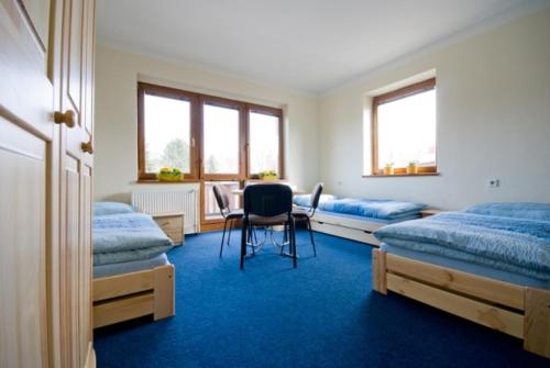 a bedroom with two beds and a table with a chair at Penzion Svet in Třinec
