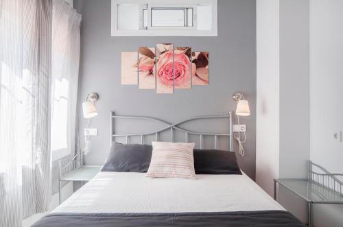 sypialnia z łóżkiem i różowym obrazem róży na ścianie w obiekcie 16 Benal Acogedor y en 1ª linea w mieście Benalmádena