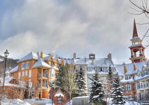 a large building with a clock tower in the snow at Tour des Voyageurs in Mont-Tremblant