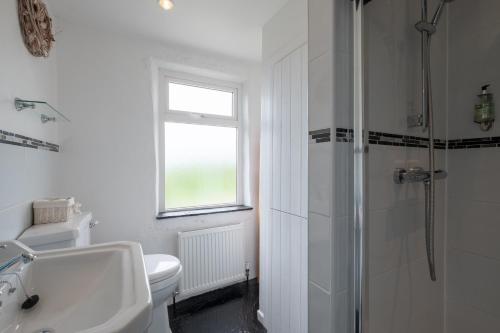 a white bathroom with a toilet and a sink at Yellow Cottage, Doolin in Knockfin Cross Roads