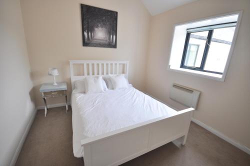 Un dormitorio blanco con una cama blanca y una ventana en Stable Cottage, Whitebridge Farm en Shaftesbury