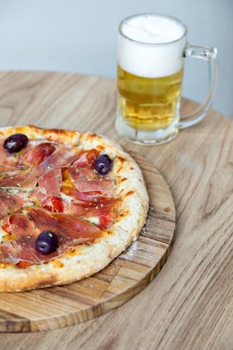 a pizza on a wooden cutting board with a glass of beer at ibis Sao Paulo Barra Funda in Sao Paulo