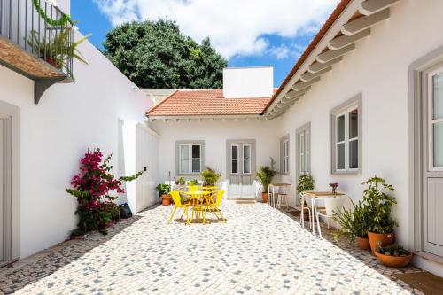 a courtyard in a white house with yellow tables and chairs at Patio São Vicente in Lisbon