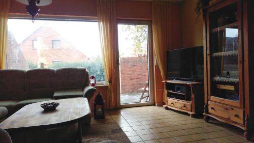 a living room with a couch and a tv and a table at Haus Spitzenblick in Friedrichskoog