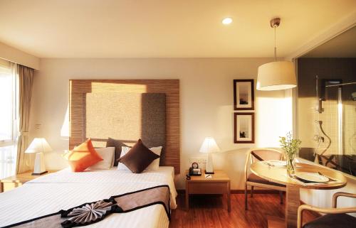 a bedroom with a bed and a table and a desk at Classic Kameo Hotel & Serviced Apartment, Rayong in Rayong