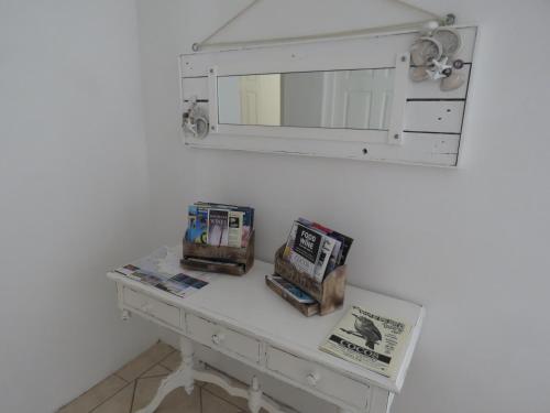 a white table with a mirror and books on it at Sea Jewel in Pearly Beach