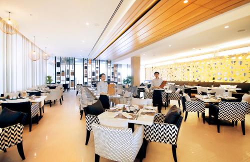 a restaurant with people standing in the middle of a dining room at Classic Kameo Hotel & Serviced Apartment, Rayong in Rayong