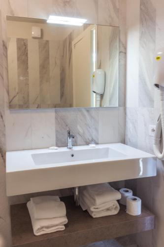 a bathroom with a sink and a mirror and towels at Villa Pioppi Hotel in Sirmione
