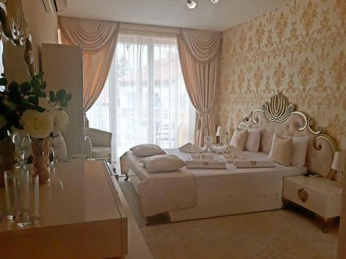 a bedroom with a white bed and a large window at Hotel Dalia - Bankya in Bankya