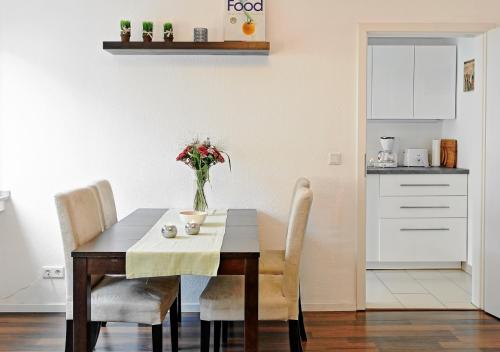 a dining room table with chairs and a vase of flowers at Design Apartment nähe Düsseldorf in Krefeld