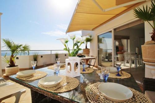ルースにあるAMAZING PENTHOUSE- panoramic sea view & tikki bar on private terrasseのダイニングルーム(テーブル、皿、グラス付)