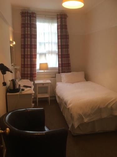 a small bedroom with a bed and a window at Elmdon Lodge in Birmingham