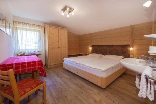 a bedroom with a bed and a sink and a tub at Appartamento Puez in Selva di Val Gardena