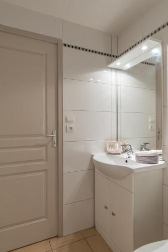 une salle de bain blanche avec un lavabo et un miroir dans l'établissement L'Hôtel du Méditerranée, à Argelès-sur-Mer