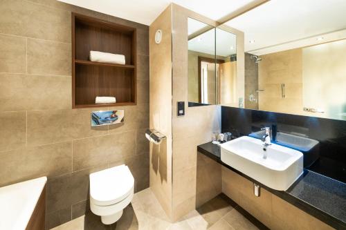 a bathroom with a sink and a toilet and a mirror at Doubletree By Hilton Sheffield City in Sheffield
