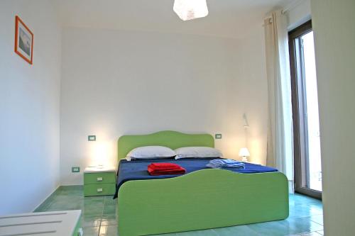 Cama verde en habitación blanca con ventana en Appartamento ALICANTE, en Canneto