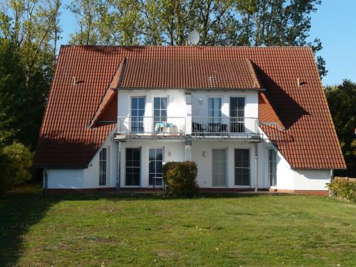 a white house with a red roof and a yard at Ferienwohnung Ankerplatz_VOLB in Ostseebad Karlshagen
