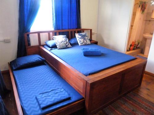 a large wooden bed with blue sheets and pillows at Miller's Guest House in Buccoo