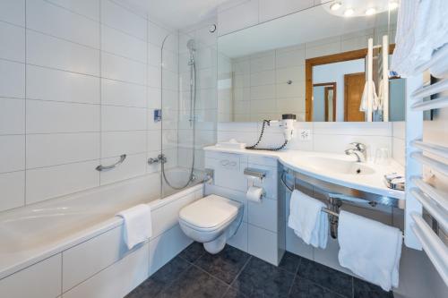 y baño con aseo, lavabo y bañera. en Hotel Rhodania, en Zermatt