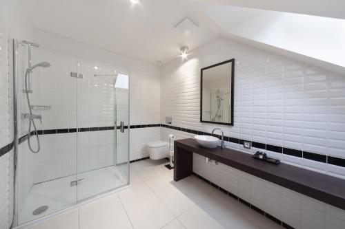 a white bathroom with a sink and a shower at Hotel Panství Dlouhá Lhota in Dlouhá Lhota