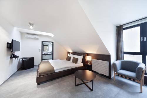a bedroom with a bed and a chair and a television at Hotel Panství Dlouhá Lhota in Dlouhá Lhota