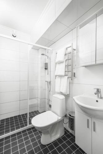 a white bathroom with a toilet and a sink at Hotel Oxelösund in Oxelösund
