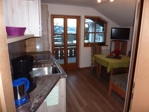 a kitchen with a sink and a table with a green table at Pension Epple in Oberjoch