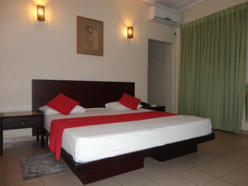 a bedroom with a large bed with red pillows at Shalimar Hotel in Colombo