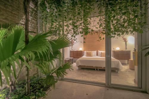 ein Schlafzimmer mit einem Bett in einem Zimmer mit Pflanzen in der Unterkunft Casa Claver Loft Boutique Hotel in Cartagena de Indias