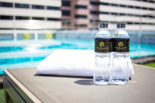 two bottles of water sitting on a table next to a pool at Graceland Bangkok by Grace Hotel - SHA Extra Plus in Bangkok