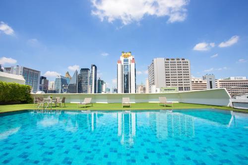 a large swimming pool with a city skyline in the background at Graceland Bangkok by Grace Hotel - SHA Extra Plus in Bangkok