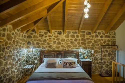 a bedroom with a bed in a stone wall at Anotopos in Ano Trikala